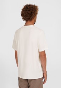 Cremefarbenes T-Shirt mit kurzen Ärmeln, schlichtes Design, weiche Textur, entspannte Passform, runder Halsausschnitt und Nahtdetail am Kragen.