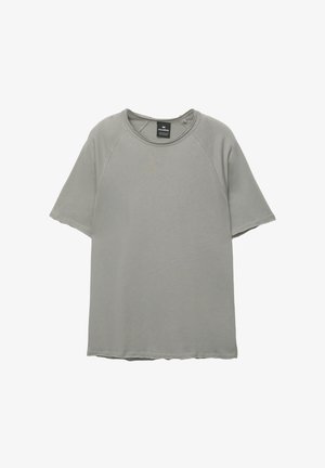 Svetlo šedé tričko s krátkym rukávom a okrúhlym výstrihom, raglánové rukávy a rovný lem. Hladká textúra s jemnými švovými detailmi.