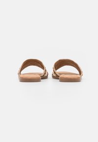 Öppen bak sandaler med vävda tygremmar, en ljusbrun fotbädd och platta gummisulor, prydda med färgglada detaljer.