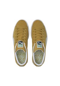 Zamszowe sneakersy w musztardowym kolorze z białymi gumowymi podeszwami. Cechy obejmują zaokrąglone noski, sznurowaną konstrukcję oraz wewnętrzny wzór geometryczny.