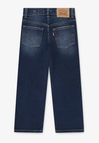 Mørkeblå denimjeans med rett passform, som har to baklommer, gullsøm og et lærmerke på livet.