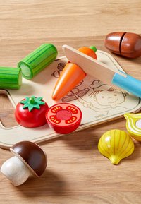 Houten speelgoed voedselset met een wortel, komkommer, tomaat, champignon en schelp, met heldere kleuren en gladde oppervlakken op een snijplank.