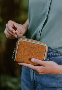 Cork wallet with light blue zipper and accents. Square shape with textured surface featuring natural cork patterns. Keychain attached.