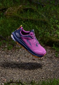 Chaussure de trail légère de couleur rose, avec des accents navy. Elle présente une tige en mesh, une semelle rembourrée et une adhérence texturée sur la semelle extérieure.
