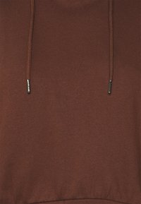 Hnědá mikina s hladkou texturou, nastavitelným stahováním a kovovými konci na šňůrkách. Jednoduchý design s žebrovaným pasem.