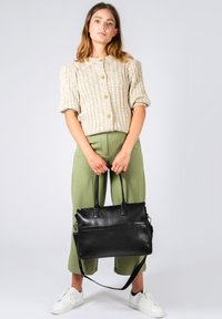 Black leather tote bag with dual handles and detachable shoulder strap, featuring a smooth texture and minimalistic design.