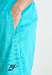 Turkos nätträningsshorts med en sidan ficka, med Nike-märket i svart på nedre vänster sida. Texturen är andningsbar och lättvikts.