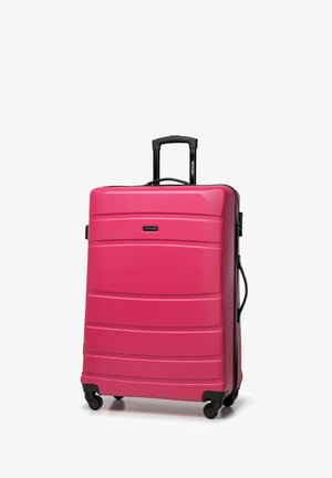 Grande valise rigide rose avec surface texturée, poignée télescopique noire, quatre roues et lignes horizontales subtiles.