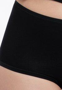 Musta hipster alusvaatteet, jotka on valmistettu sileästä puuvillasta, saumattomalla muotoilulla ja pehmeällä elastisella vyötärönauhalla, jotka tarjoavat tiukan istuvuuden ja minimoidun tekstuurin.