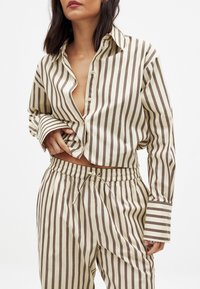 Striped, beige and brown pajama set; shirt features a button-down front and long sleeves, pants have an elastic waistband with drawstring.