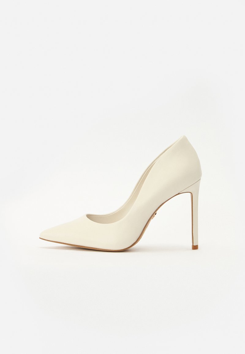 Valkoiset saappaat korkokengät teräväkärkisillä, sileä nahkapinta ja hoikka stiletto-korko. Minimalistinen muotoilu, jossa on hienovaraisia yksityiskohtia.