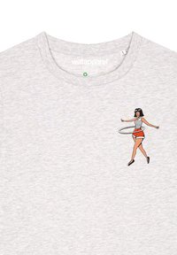 Graues Baumwoll-T-Shirt mit einem Bedruckten Design einer Frau, die mit einem Hula-Hoop-Reifen spielt. Sie trägt rote Shorts und ein gestreiftes Oberteil sowie schwarze Schuhe.