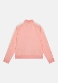 Lichtroze trainingsjack met crèmekleurige zijsstripes, geribbelde kraag en manchet. Gladde stof met een casual pasvorm en sportief ontwerp.