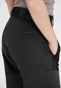 Svarta utomhusshorts med en avslappnad passform, featuring elastisk midja, sidofickor och en tagg-logotyp på baksidan. Slätt, lätt material.