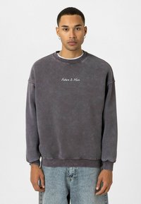 Grijze, katoenen sweatshirt met een relaxte pasvorm, ronde hals en geborduurde tekst "De Toekomst Is Hier" op de borst. Casual ontwerp met verlaagde schouders.