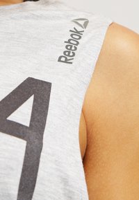Top atletico senza maniche grigio con grafica nera '4' e logo Reebok sulla spalla, realizzato in un tessuto morbido e testurizzato.