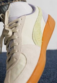 Athleticus cipő bézs bőr felsőrésszel, szürke kiegészítőkkel és texturált zöld csíkkal. Átlátszó narancssárga gumitalppal rendelkezik.