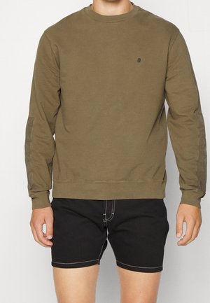 Sweatshirt olive vert à manches longues avec un col rond, présentant un logo discret sur la poitrine et des détails cousus sur les épaules.