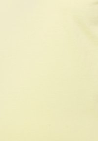 T-shirt amarelo claro feito de algodão macio. O tecido tem uma textura suave com um design simples e sem padrões ou acentos visíveis.