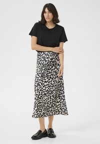 Zwarte korte mouwen t-shirt gecombineerd met een leopardprint, knielange rok in roomwit en zwart, met een soepele textuur en een uitlopende zoom.