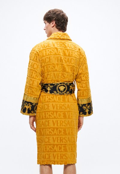 Rumeno kopalno rjuho z reliefnim vzorcem logotipa "VERSACE". Črni pas z okrašenimi zlatimi poudarki in vzorčastimi rokavi. Mehka tkanina.