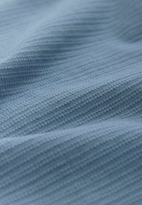 Világos kék, textúrált anyag, finom szőtt mintával, amely hullámokat és redőket mutat, ezáltal fokozva tapintható megjelenését.