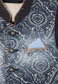 Blå mönstrad väst med kontrasterande vit paisleymönster, försett med bronsknappar och en blå prickig näsduk, kantad i brunt.