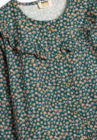 Vestido infantil de algodón en un color verde oscuro con un estampado floral, que presenta flores rosas y naranjas, un cuello con volantes y un cierre de botón dorado.