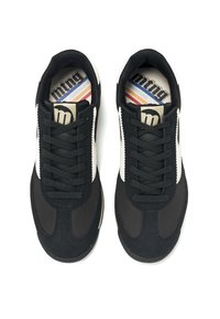 Zapatillas negras que combinan materiales sintéticos y ante, con una franja blanca, puntera redonda y cordones negros planos en la parte superior.