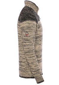 Beige und schwarzer Strickpullover mit hohem Kragen, der ein strukturiertes Muster und ein kleines rotes Logo am Oberarm aufweist.