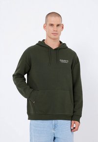 Olijfgroene hoodie van zacht materiaal, met een voorzak, capuchon met trekkoord en witte logotekst op de linkerborst.
