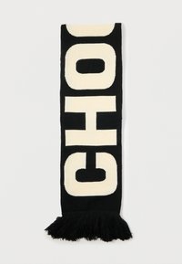 Sciarpa bianca e nera con grandi lettere in grassetto che spellano "CHOC" e con estremità frangiate, esposta piatta su uno sfondo bianco.