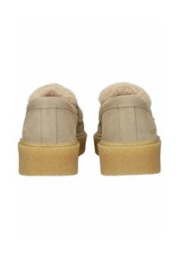 Pair of beige suede shoes with thick rubber soles and fuzzy lining, viewed from the back against a white background.