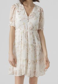 Robe fleurie à col en V et manches bouffantes. Confectionnée dans un tissu léger, ornée de fleurs roses et jaunes douces, avec une jupe à volants.