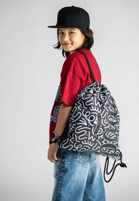 Zaino con cordino di colore nero con motivi astratti bianchi. Realizzato in tessuto resistente. Presenta spallacci regolabili e una chiusura superiore con chiusura a coulisse.