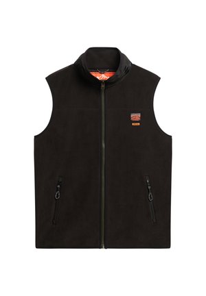 Chaleco de forro polar negro con cuello alto, cremallera frontal y dos bolsillos laterales con cremallera. Presenta un parche con logo en el lado izquierdo del pecho. Textura suave.