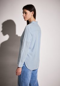 Camicia a maniche lunghe a righe blu chiaro e bianche con colletto button-down e orlo arrotondato, realizzata in tessuto liscia, con yoke sul retro.