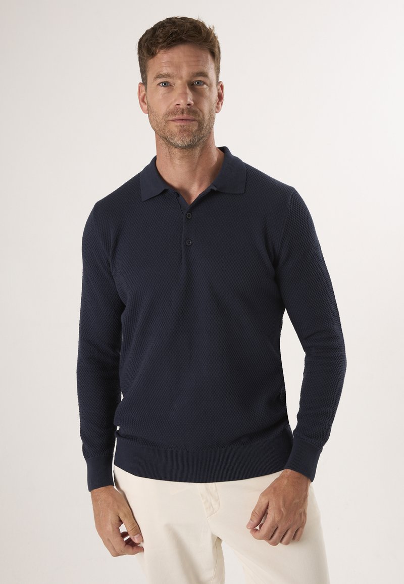 Mørkeblå langærmet polo shirt med et struktureret mønster, krave og tre knapper, parret med lyse chinos. Casual pasform.
