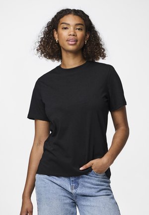T-shirt de algodão preta com decote redondo e mangas curtas. O tecido parece suave, ajustando-se de forma solta, combinado com jeans de tom azul claro.