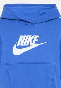 Sudadera azul de Nike hecha de una mezcla de algodón, con un gran logo blanco en el pecho, que cuenta con un bolsillo frontal y una capucha ajustable con cordón.