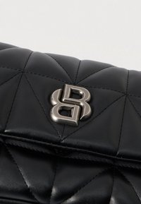 Crna kvadratna kožna torbica s srebrnim preklopnim naglaskom u obliku međusobno povezanog B loga na sredini preklopa.