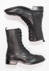 Stivaletti neri in pelle con design brogue, lacci sul davanti, cerniera laterale e tacco basso a blocco. Texture liscia con dettagli sottili.