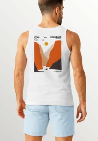 White tank top with a graphic design on the back. The design features orange mountains, a yellow sun, two birds, and text reading "UTAH Lake Powell" and "COLORADO Neverless."