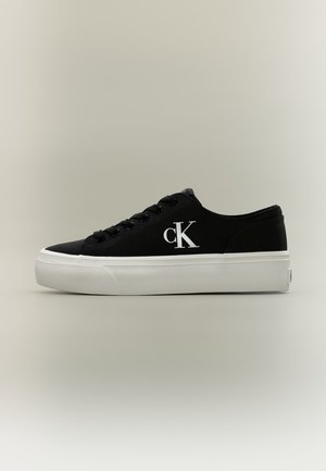 Baskets noires Calvin Klein à lacets, avec une épaisse semelle plateforme blanche, vues de profil.