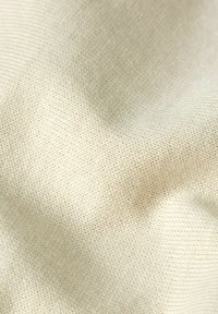 Licht beige gebreide stof met een gladde, zachte textuur en een fijne, uniforme weefpatroon.