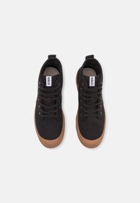 Sneakers neri in tela con suole in gomma marrone, dotati di punta rotonda, design con lacci e etichetta del marchio sulla linguetta.
