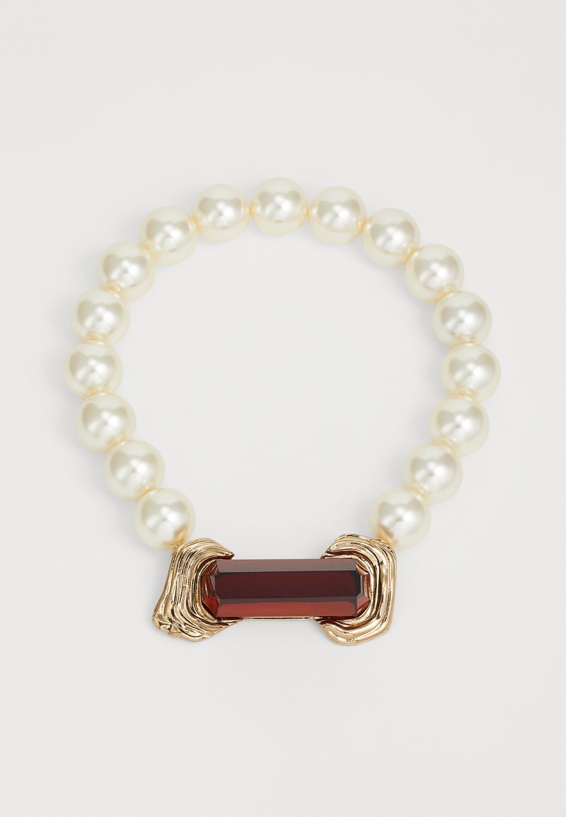 Pärlkaelakee, millel on punane vääriskivi keskus, raamitud kuldsetes aktsentides. Pärlid on siledad ja ümmargused, pakkudes läikivat viimistlust.