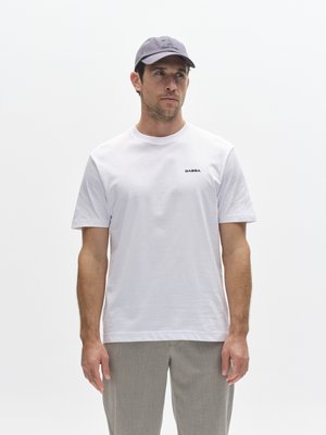 Valge lühikeste varrukatega t-särk väikese musta "GABBA" logoga. Sobitatud heledate hallide pükste ja halli nokamütsiga, millel on tikitud logo.