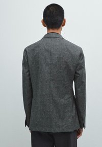 Grey textured blazer with a tailored fit, single vent at the back, and notch lapels. Subtle pattern visible on the fabric.