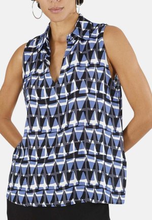 Blusa senza maniche con colletto e motivo geometrico a triangoli blu, neri e bianchi indossata da una persona con orecchini a cerchio.